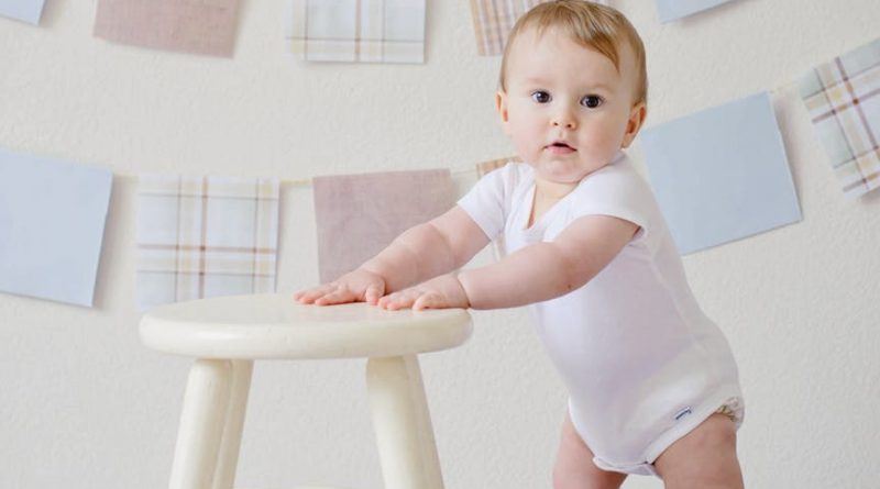 baby holding white wooden stool