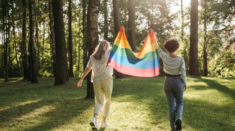 back view of two women holding a rainbow flag